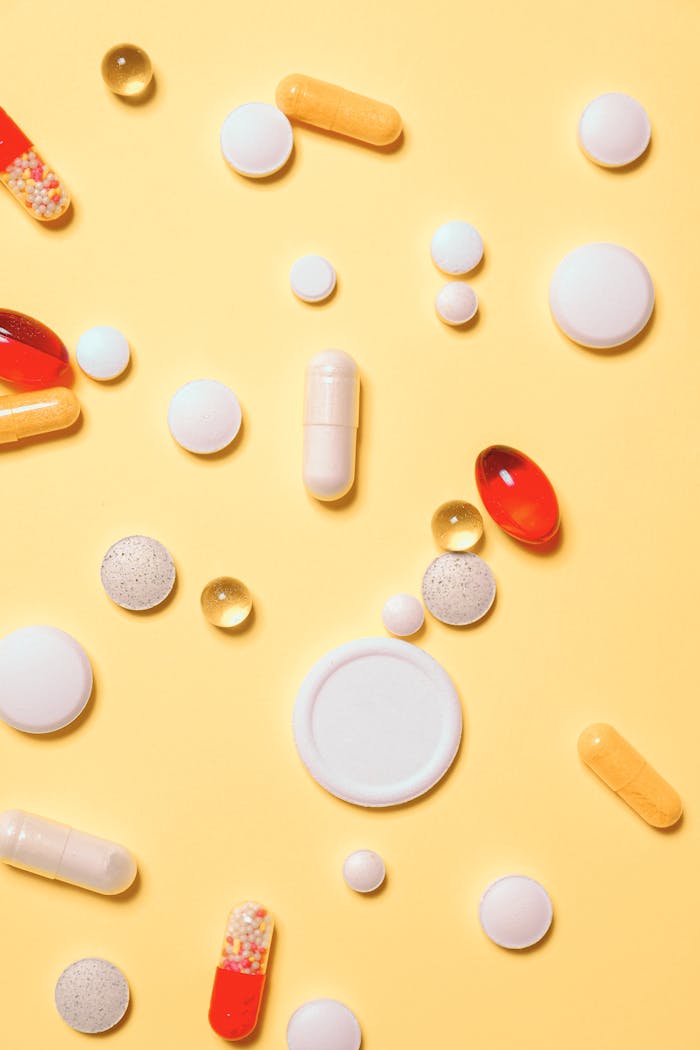 Colorful assortment of pills and capsules on a vibrant yellow background.